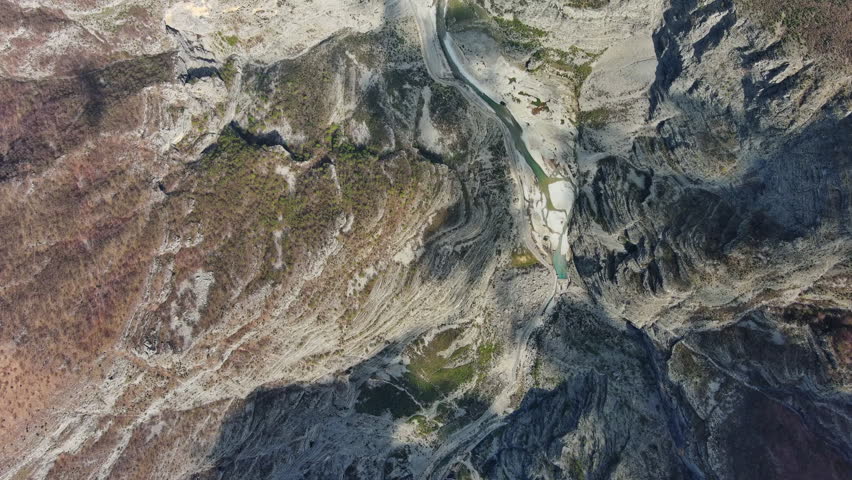 Aerial top view of deep mountain canyon with rocky cliffs and green forest. Prokletie park in Albania and Montenegro, 4k