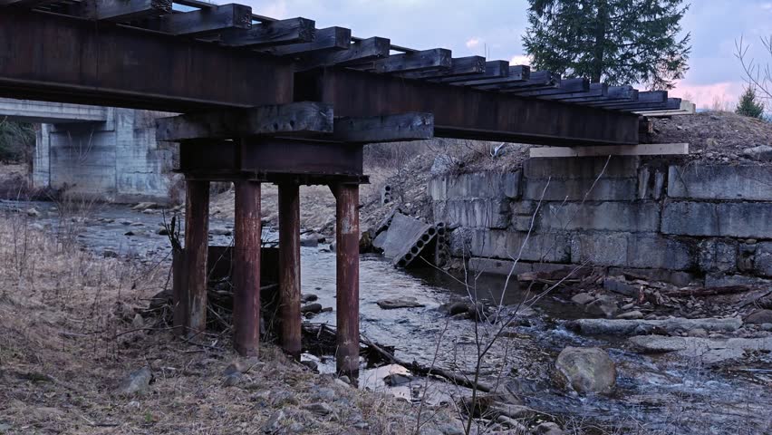 Old industrial bridge structure crossing a rocky mountain stream.