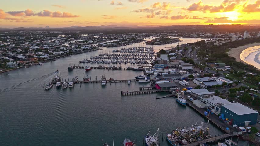 Sunset over Mooloolaba Harbour, Sunshine Coast, Queensland. Calm waterways, marina boats, fishing vessels, jetties and waterfront homes glow under warm morning light in this scenic coastal aerial view.