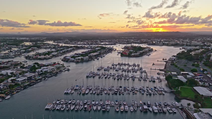 Sunset over Mooloolaba Harbour, Sunshine Coast, Queensland. Calm waterways, marina boats, fishing vessels, jetties and waterfront homes glow under warm morning light in this scenic coastal aerial view.