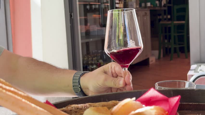 A close-up shot of a man setting down red wine beside a bread basket
