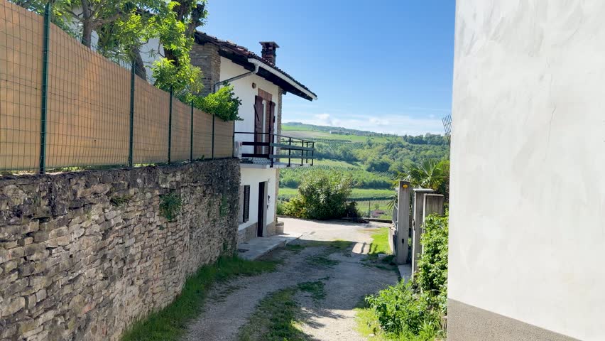 A slow camera pan reveals a rustic stone house overlooking lush Italian vineyard hills