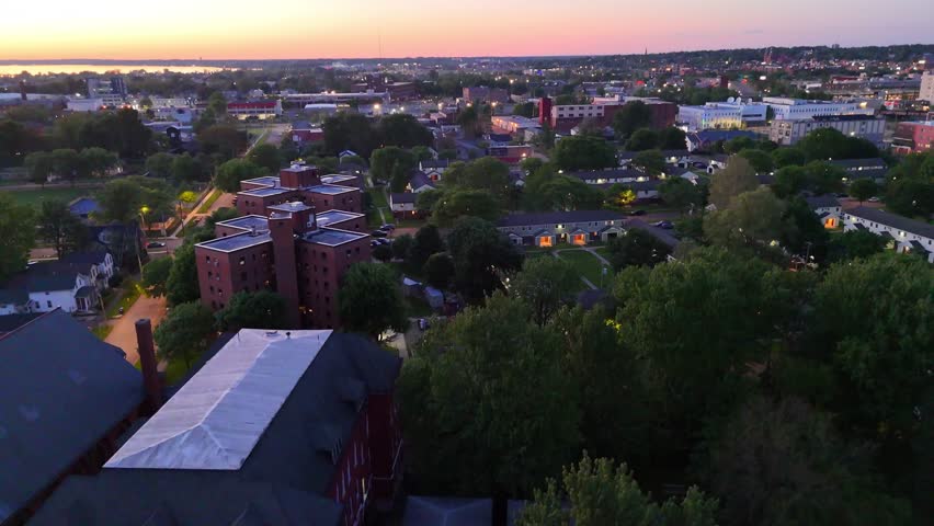 Descending down over a neighborhood as dusk has fully taken over but is also close to being taken over by the night as well.