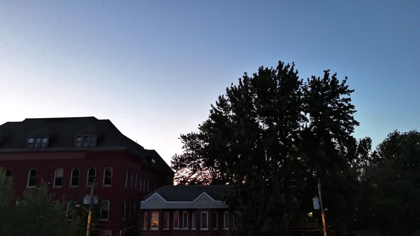 Descending down over a neighborhood as dusk has fully taken over but is also close to being taken over by the night as well.
