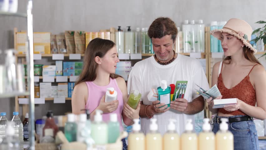 Man with wife and teen daughter customers in drugstore choose with different products. Parapharmacetical products, French body care cosmetic, pills and medicines are in drug store assortment