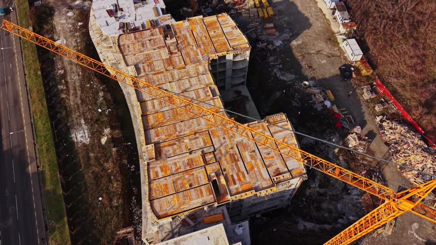 A construction site in Nesebar Bulgaria shows workers and heavy machinery. A crane lifts materials for a new building. The area is busy with ongoing construction tasks.