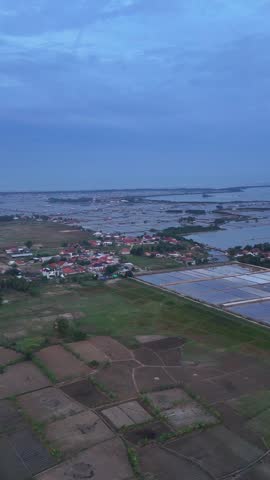 Aerial view of cultivated fields and aquaculture ponds in a rural landscape at dusk