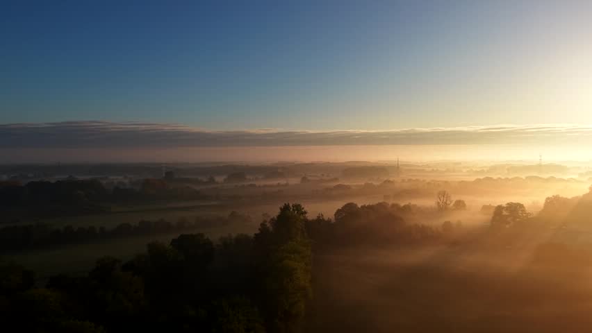 Golden sunrise with misty fields and farmland landscape in America. Aerial dolly forward wide shot. Quiet and peaceful rural suburb area. Majestic nature scenery in USA. Panorama view.