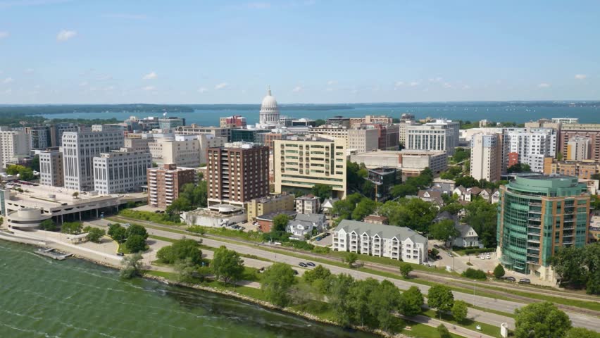 Panoramic Aerial View of Madison Skyline and Wisconsin State Capitol Building.  The iconic white dome of the Wisconsin State Capitol building stands prominently in the center, with the expansive water real estate buildings. 