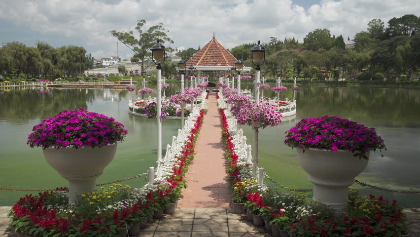 Awesome walkway to scenic pavilion among beautiful lake of Dalat city (Da Lat), Vietnam. Amazing pathway decorated with white, red and pink flowers. Dalat is a popular tourist attraction of Asia.