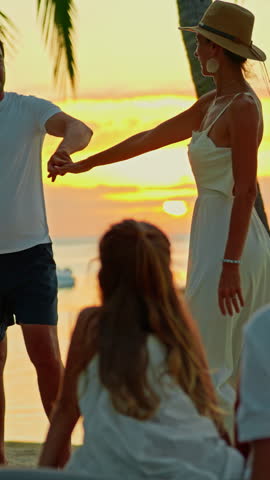 Silhouette couple are dancing at sunset and on beach ocean. Their children sit and watch their parents dance. A wonderful family vacation and trip