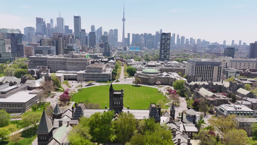 Aerial view flying forward over University College and tilting down to frame the large, vibrant green lawn of King