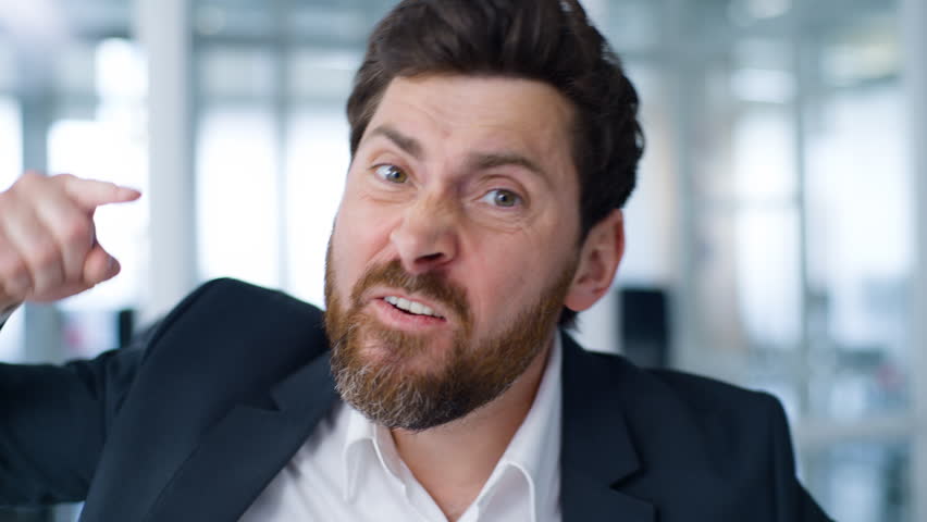Close up negative angry Caucasian middle-aged business man talking with aggression looking at camera senior businessman mature male entrepreneur talk furious work problem working video call in office
