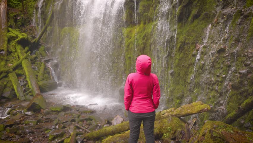 Woman hiker enjoying the view of the lush forest and moss at Proxy Falls in Oregon, USA.