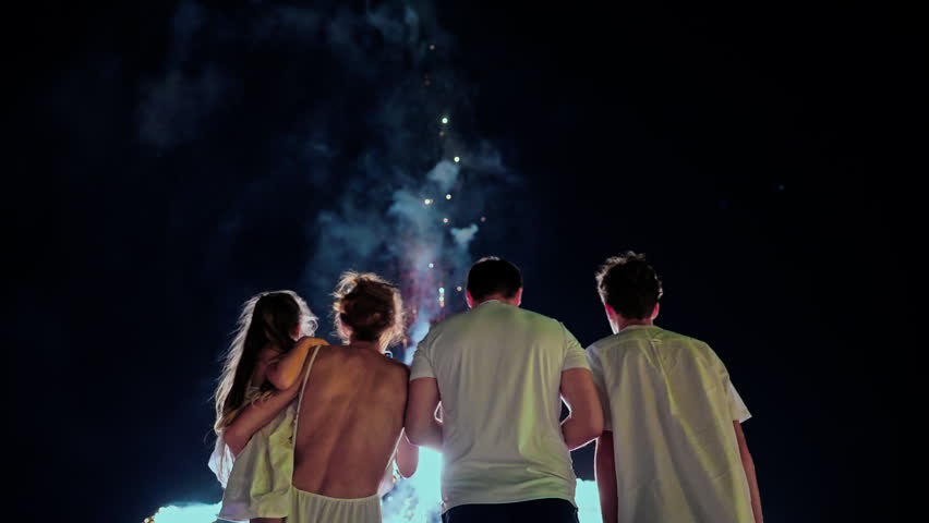 Parents with kids watch the beautiful fireworks on the ocean coast