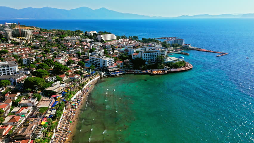 Drone view of Ladies Beach in Kusadasi, Turkey coastline. People swim and relax along the shore as hotels and blue water create a summer travel scene.