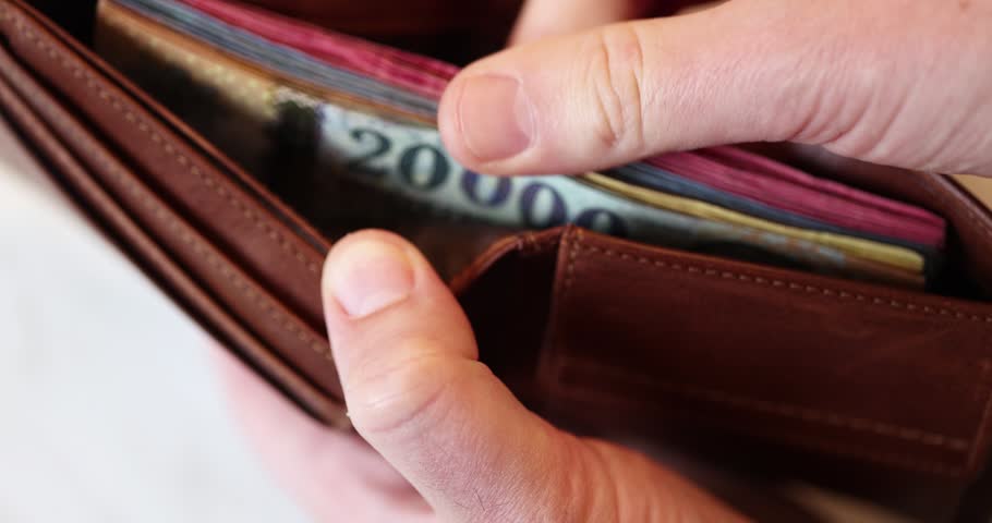 Man checking a lot of hungarian banknotes inside him leather wallet for ready a good spending day.