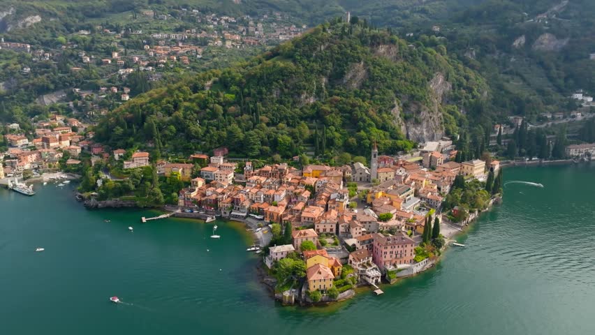 Scenic aerial view of Varenna town on the shore of Lake Como, Italy. Picturesque architecture of Varenna at Como Lake. Colorful historic houses stand out against the lush green hill, Italy