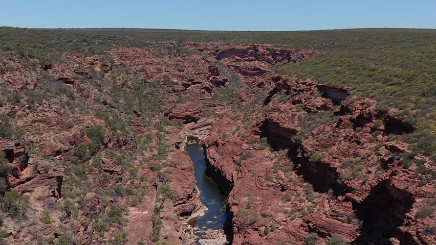 Aerial View of Z Bend Red Rock Canyon With Meandering Murchison River and Rugged Cliffs Under Clear Blue Sky, Kalbarri National Park, Western Australia.