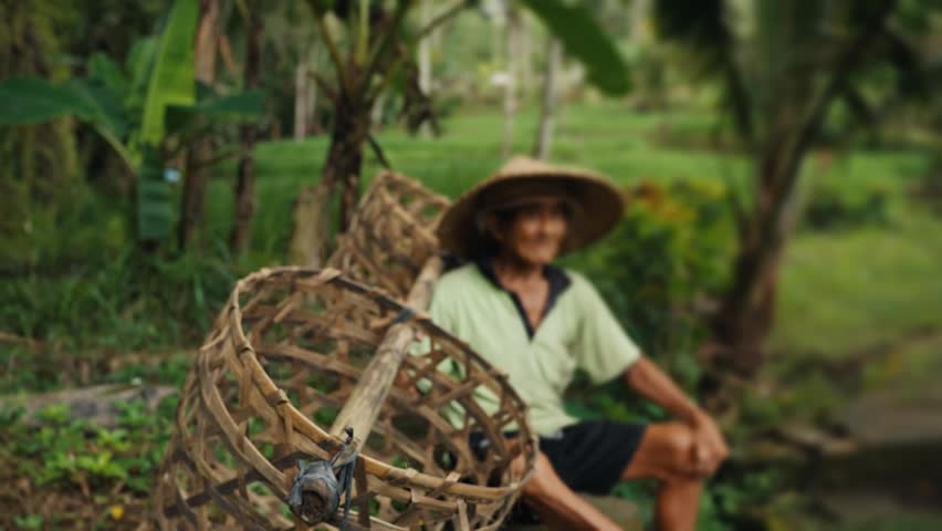 Elderly indonesian farmer resting with baskets
