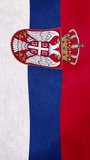 Photorealistic macro close-up of a Serbian national flag with rich woven fabric texture and detailed embroidery, featuring horizontal tricolor bands in white, cobalt blue, and deep red. The composition highlights an ornate double-headed eagle coat of arms with a red shield and golden crown, rendered in intricate stitched detail with metallic gold thread highlights. Captured in vertical orientation with cinematic lighting that enhances fabric depth, natural folds, and realistic shadows. Shallow depth of field keeps the central emblem sharply focused while edges softly blur, creating a premium patriotic and symbolic visual. Ideal for themes of national identity, European heritage, sovereignty, history, and cultural symbolism. - Powered by Shutterstock - Get 15% off with code: PIKWIZARD15