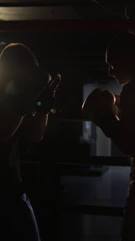Silhouette of two fighters sparring in a boxing ring