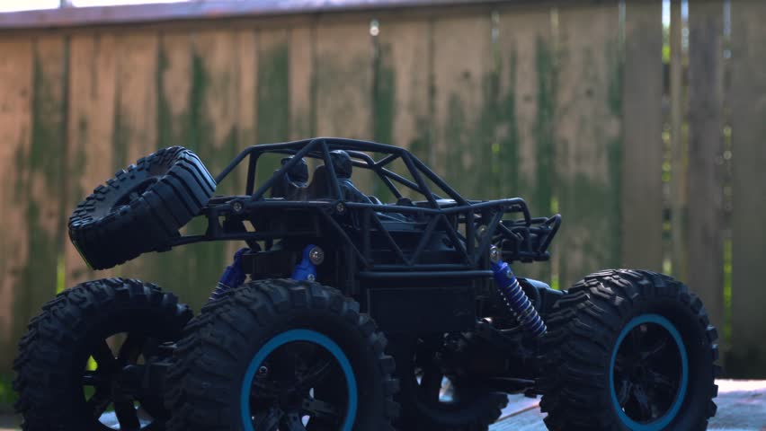 off-road toy cars turn with big tires art creative in water splashes 360 degree rotation on dark background with red backlight