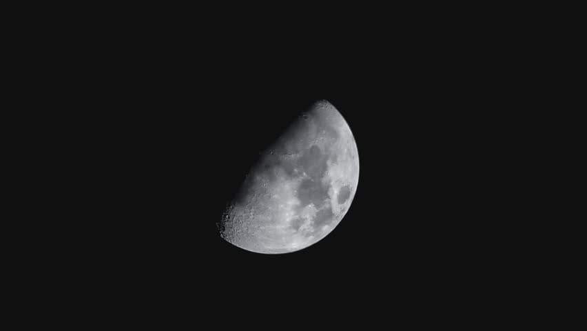 Detailed close up shot of a sharp first quarter moon phase against a pitch black night sky, showing lunar craters and surface details.