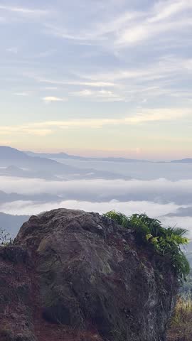 Person Standing on Cliff Overlooking Foggy Mountains
