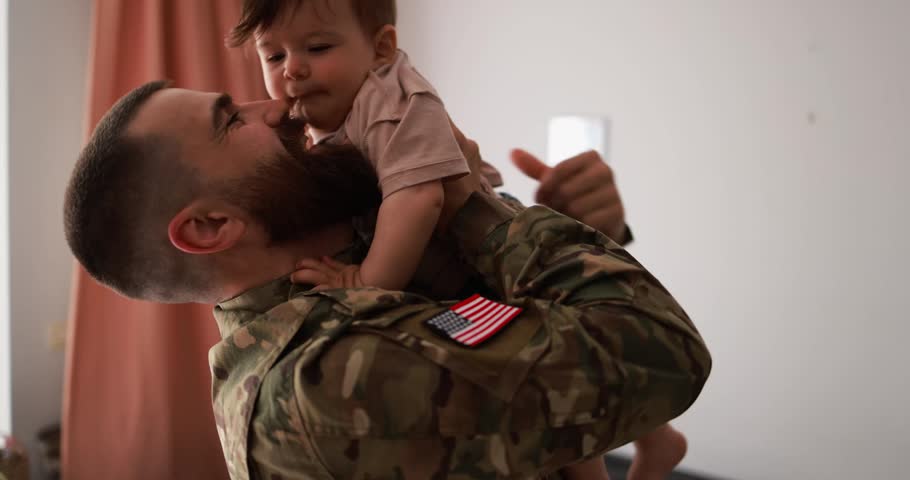 American soldier man in military uniform having playful time with little son at home - Emotional and happy military homecoming concept