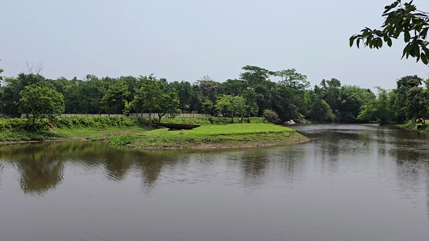 Natural pond landscape with green trees and boat on grassy