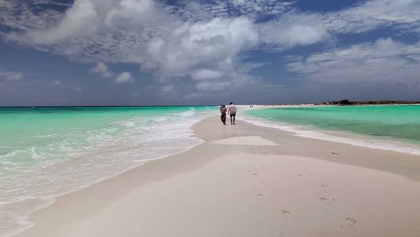 loving couple explores a secluded sandbank in crystalline Caribbean waters, capturing a serene moment of connection and blissful island escape in in Cayo de Agua Los Roques Venezuela