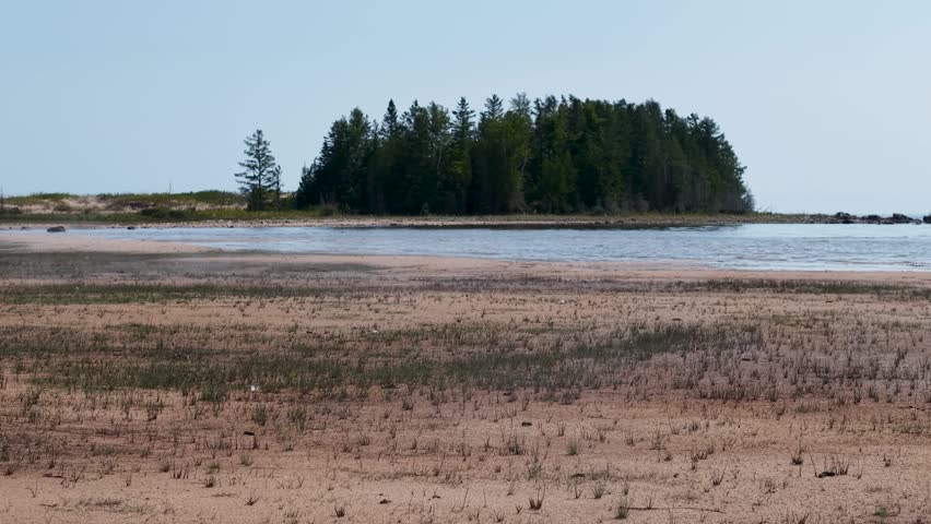 A scenic view of a small tree-covered island beyond a calm lake in Michigan