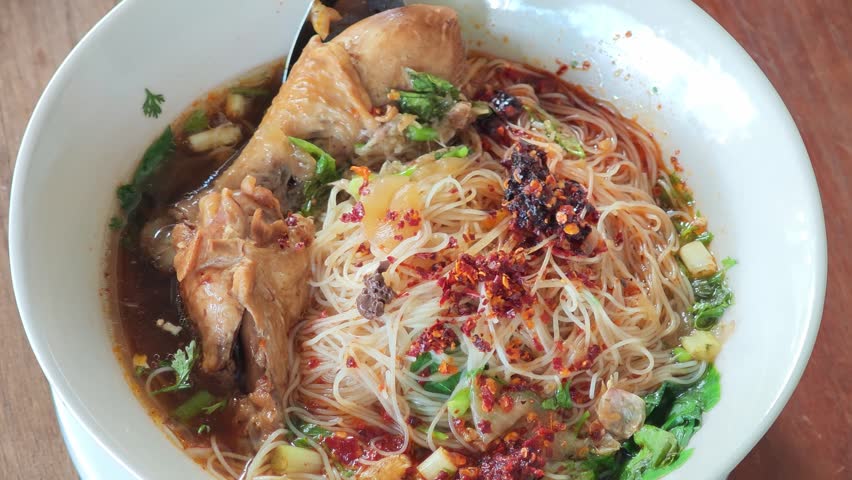 chicken noodle soup with thin rice noodles in ceramic bowl