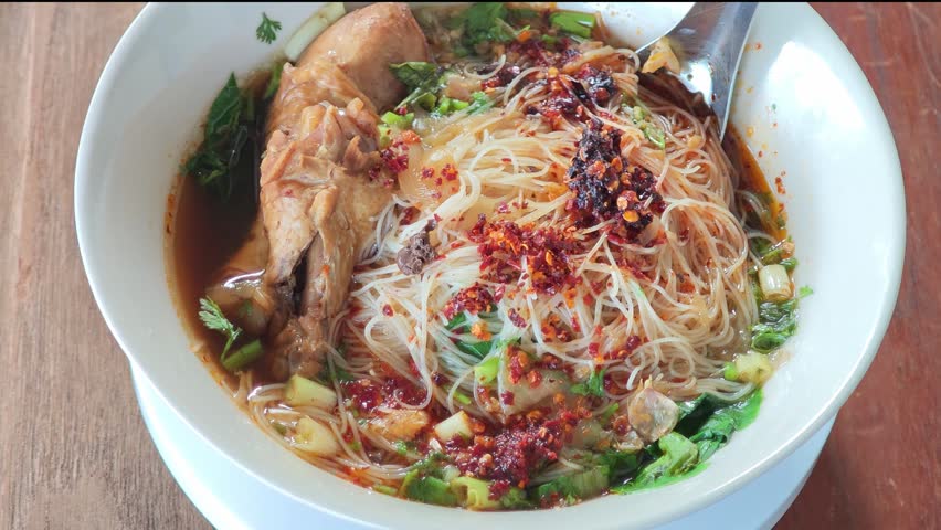 chicken noodle soup with thin rice noodles in ceramic bowl