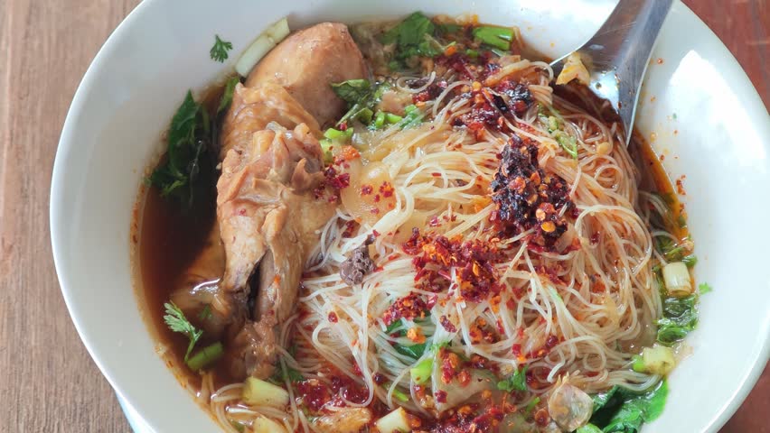 chicken noodle soup with thin rice noodles in ceramic bowl