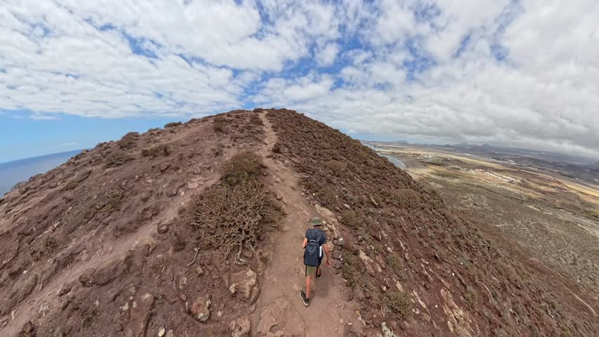 Hiking trail on Montana Roja, Tenerife, Canary Islands, volcanic hillside ascent with ocean view and dramatic cloudy sky, shot on 360 camera