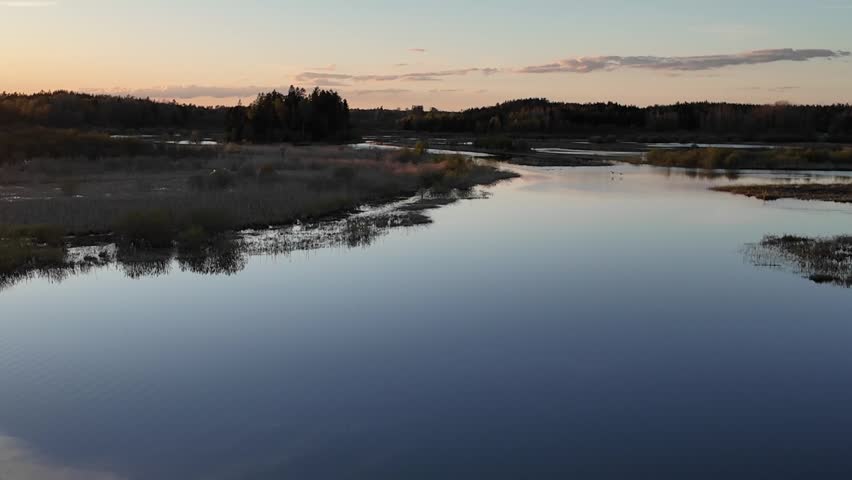 Evening wetland water at sunset. Peaceful sunset view over wetland water with birds visible in the scene.