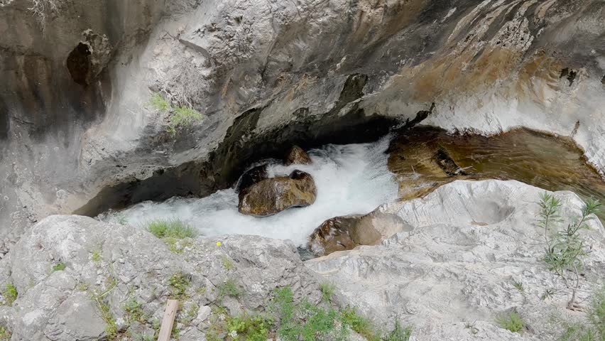 Wild mountain river stream rushing through colorful rocky canyon gorge
