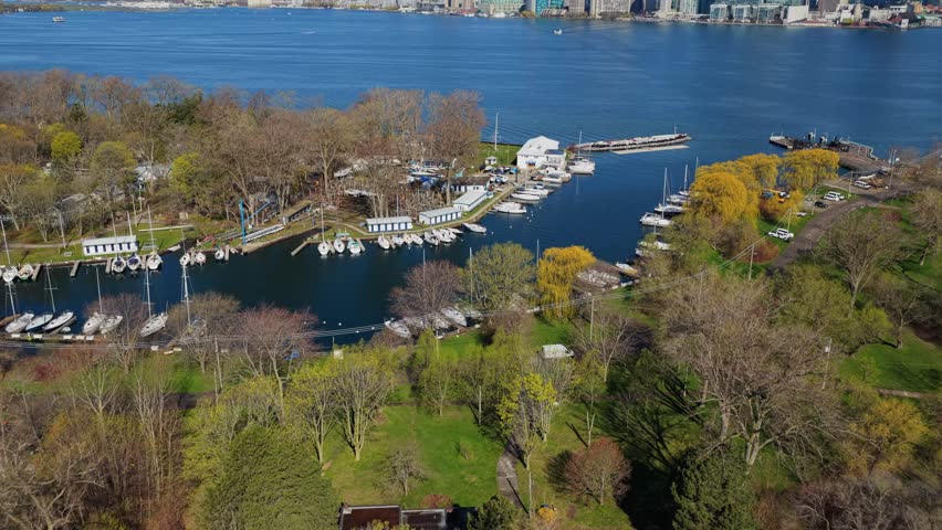 Cinematic aerial ascent over Toronto Islands park revealing iconic downtown skyline with modern skyscrapers and financial district across placid Lake Ontario