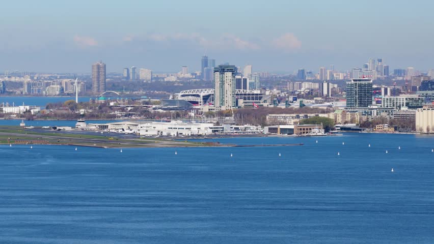 Telephoto shot of Billy Bishop Toronto City Airport with Humber Bay shores and Ontario Place background showcasing Toronto