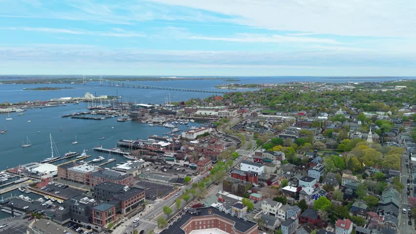 Newport Harbor and bridge wide aerial view, drone shot showcasing the bustling marina docks, moored sailboats, and the Claiborne Pell Bridge spanning the bay in Rhode Island.