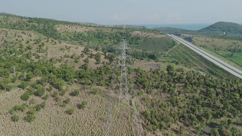 Expansive Aerial Landscape Featuring Dense Vegetation, Power Lines, and a Coastal Roadway east java