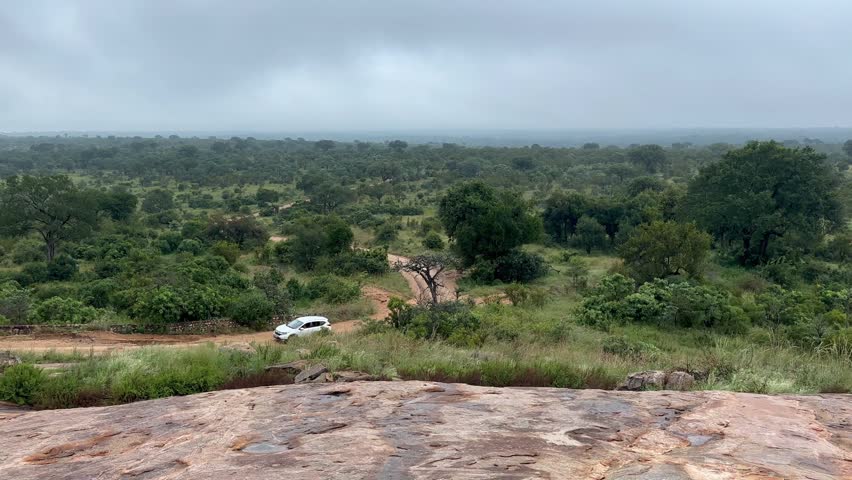 Car travelling across rocky landscape in Kruger National Park, South Africa.