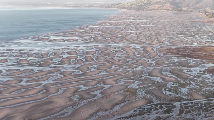 Aerial drone view of tidal sand patterns along South Island coastline in New Zealand, climate and abstract natural landscapes.