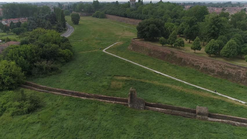 Aerial view of the ancient city walls and green fortifications with walking paths and lush trees in Ferrara, Emilia-Romagna, Italy.