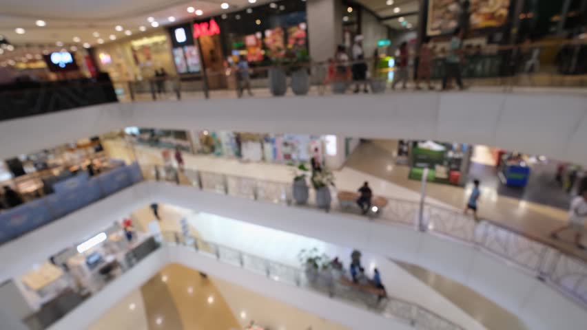 Shopping mall interior modern retail center with blurred people on multi level balcony corridor and bright modern walkway near store front on multi level retail center