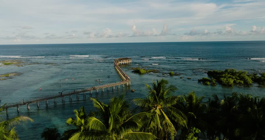 Pier with viewing hut surrounded by surfers in the reef waters. Cloud 9 Surfing Area. Siargao, Philippines.