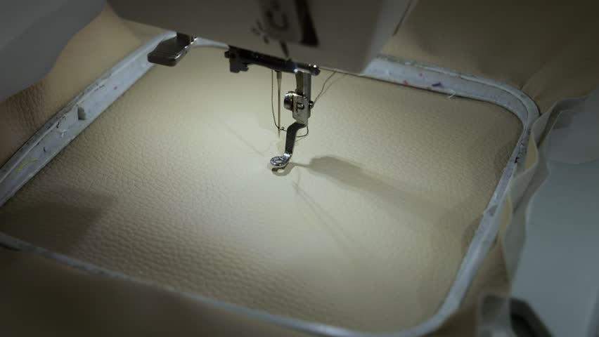 Machine embroidery of circles with black thread on light brown leather fabric.