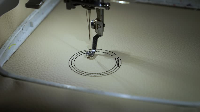 Machine embroidery of circles with black thread on light brown leather fabric.